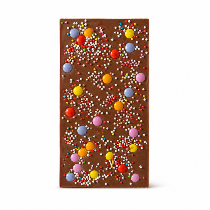 Festlig mjölkchoklad med färgglatt godis och strössel på vit bakgrund
